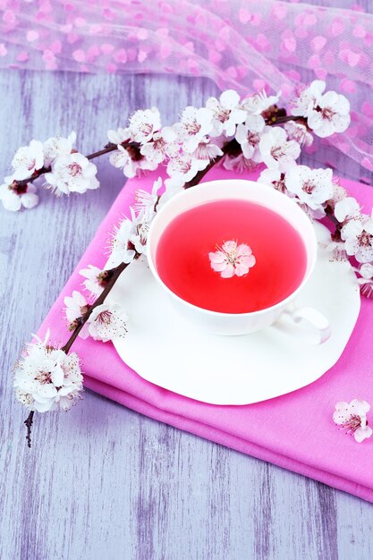 Photo fragrant tea with flowering branches on wooden table close-up