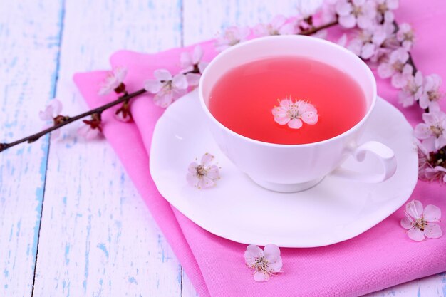 Fragrant tea with flowering branches on wooden table closeup