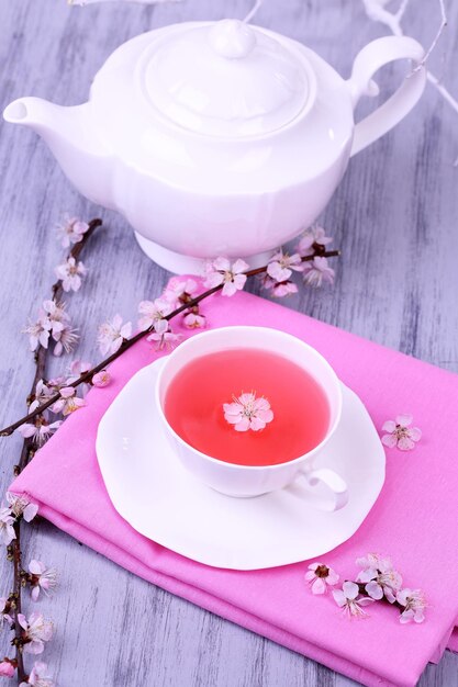 Fragrant tea with flowering branches on wooden table closeup