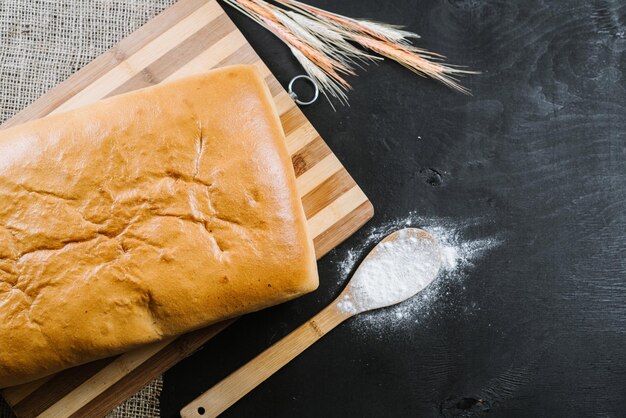 Fragrant white bread and wheat flake on black wooden background