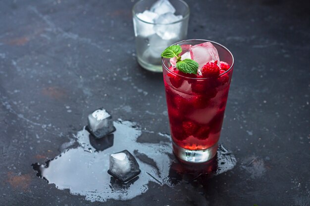 Framboos alcoholische cocktail met likeur, ijs en munt op een donkere ondergrond. Framboos Mojito. Verfrissend koel drankje, limonade of ijsthee in een glas. Sluit, kopieer ruimte voor rustige tekst