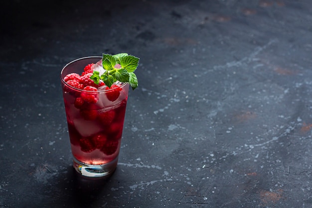 Framboos alcoholische cocktail met likeur, wodka, ijs en munt op een donkere muur. Framboos Mojito. Verfrissend koel drankje, limonade of ijsthee in een glas. Sluit, kopieer ruimte voor rustige tekst