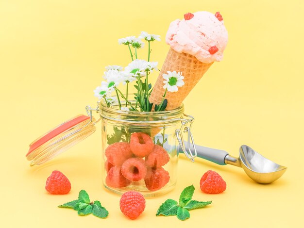 Frambozenroomijs in een wafelhoorntje met zomerbloemen verse bessen in een glazen pot