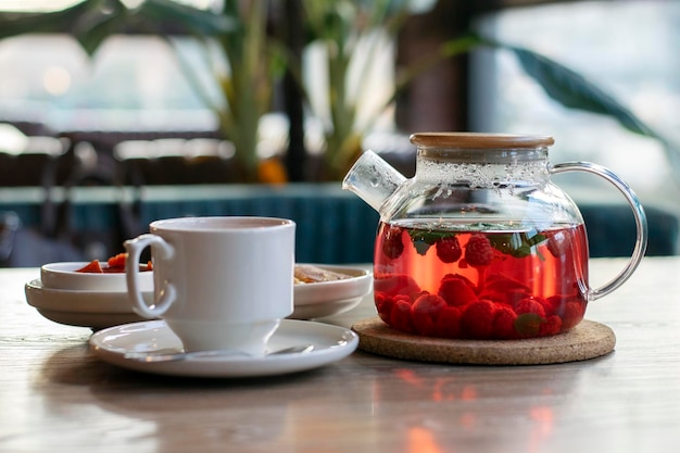 Frambozenthee met munt in een transparante theepot op een tafel in een café.