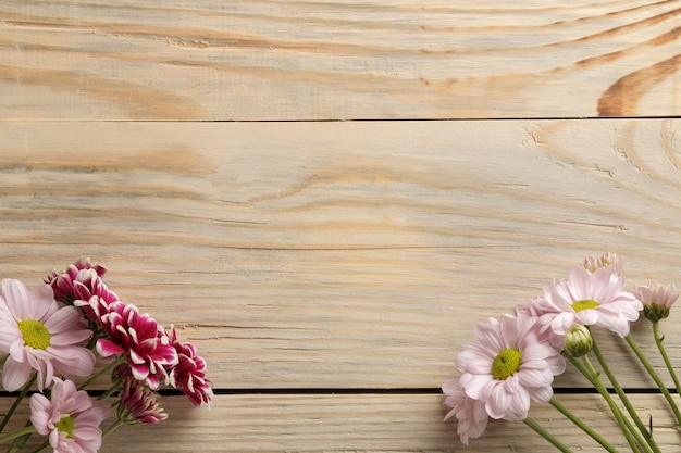 Foto cornice di fiori autunnali di crisantemi su uno sfondo di legno naturale. vista dall'alto