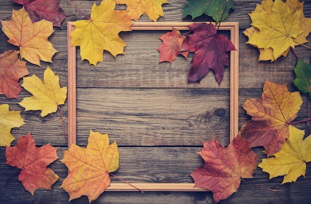 Frame of autumn leaves on wooden background