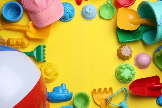 Frame of beach sand toys on yellow background flat lay Space for text