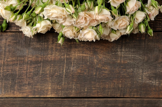 Frame of beautiful mini roses on a brown wooden table