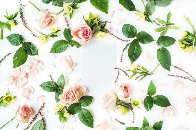 Frame of blank paper, pink roses, branches, leaves and petals isolated