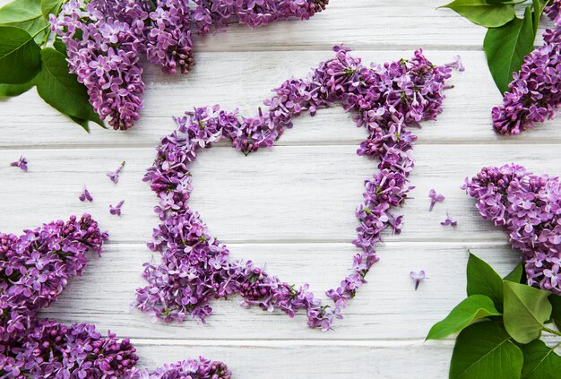 Frame of branches and flowers of lilac on a table in the shape of a heart,  top viev, flat lay, copy space for  Easter, mother's day, women's day