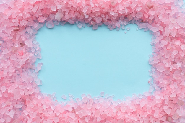 Frame of coarse crystals of pink sea salt on blue