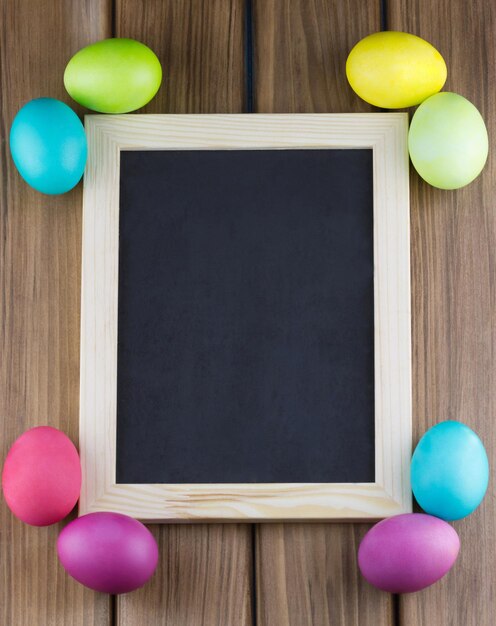 A frame of colorful easter eggs on a wooden background