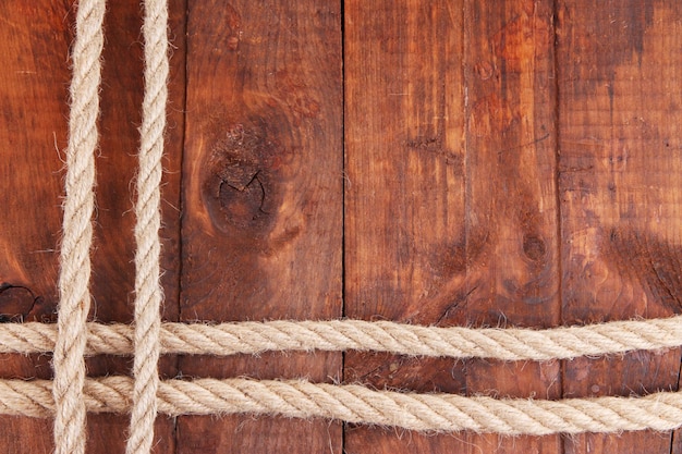 Frame composed of rope on wooden background