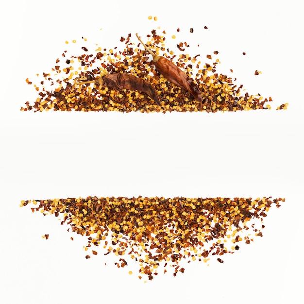 Frame of crushed red cayenne pepper, dried chili flakes and seeds isolated on a white