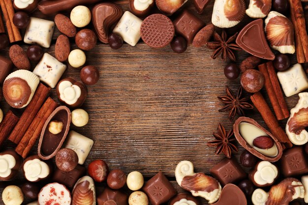 Frame of different kinds of chocolates on wooden table close-up