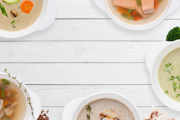 Frame of different soups on white wooden table