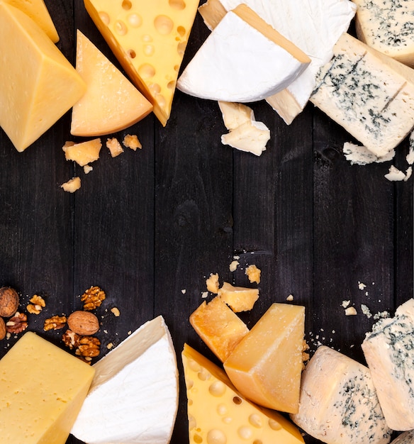 Frame of different types of cheese on black table