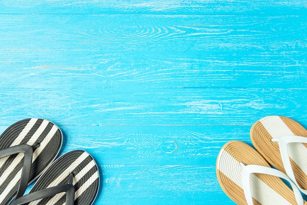Frame elegant female slippers on blue wooden background, copyspace, summer vacation.