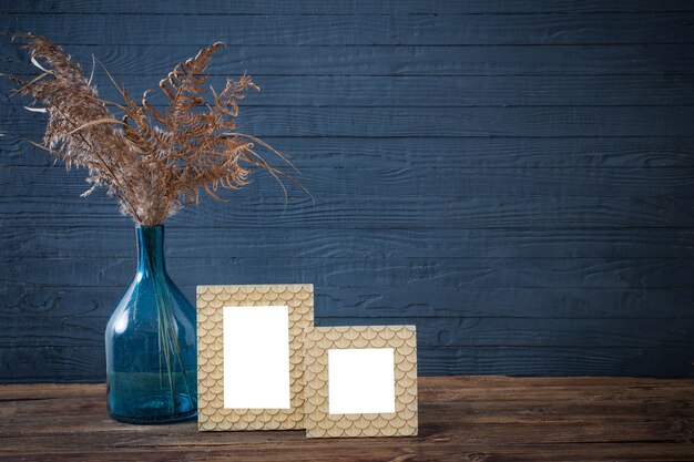 Frame en gedroogde bloemen in blauwe glazen vaas op oude houten tafel