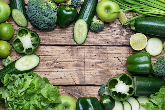 Frame forms the heart Fresh green vegetables and herbs on a wooden background. Copy space.