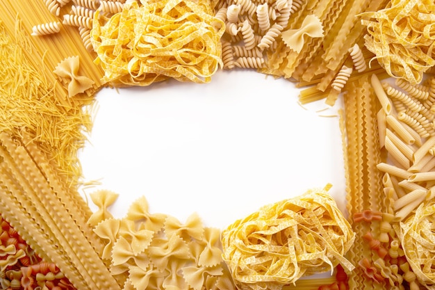 Frame from Assorted varieties of pasta wallpaper. Mix macaroni, spaghetti on white background with copy space