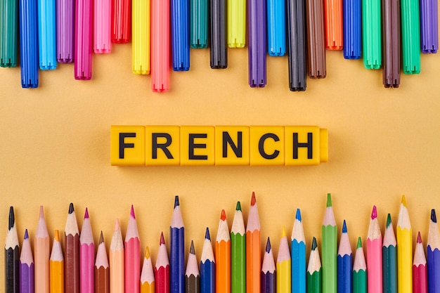 Frame from colorful pencils and word FRENCH written on plastic cubes