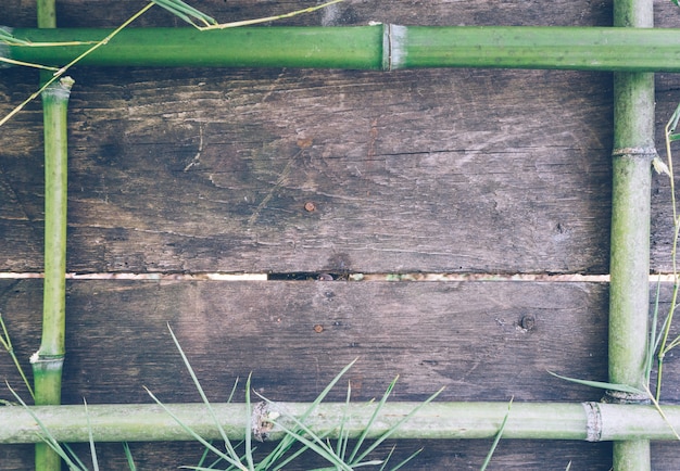 Frame from green bamboo on an old rustic wooden table.