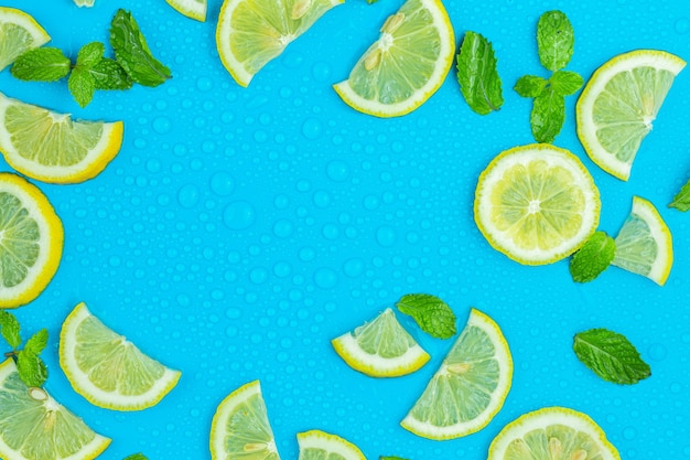 Frame from lemon slices and mint leaves on blue pastel table top view