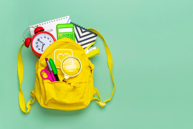 Frame from of office supplies Paper clips scissors pens felttip pens sharpener backpack calculator s