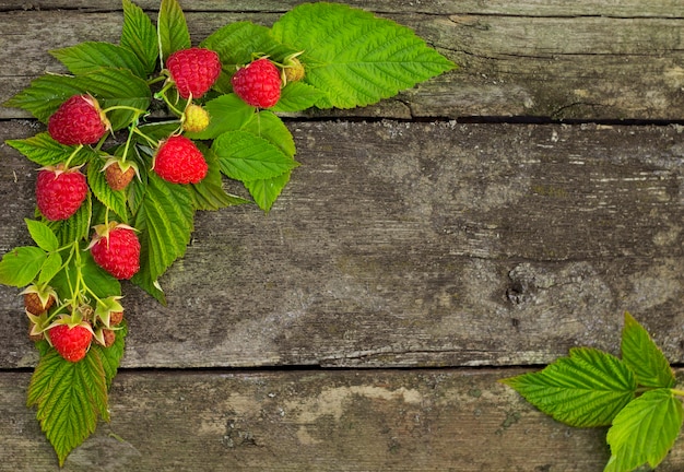 Frame from Raspberries on the Old Wooden Table Background with space for your text,  Summer Fruits, Sweet Ripe Berries, Green Leaves