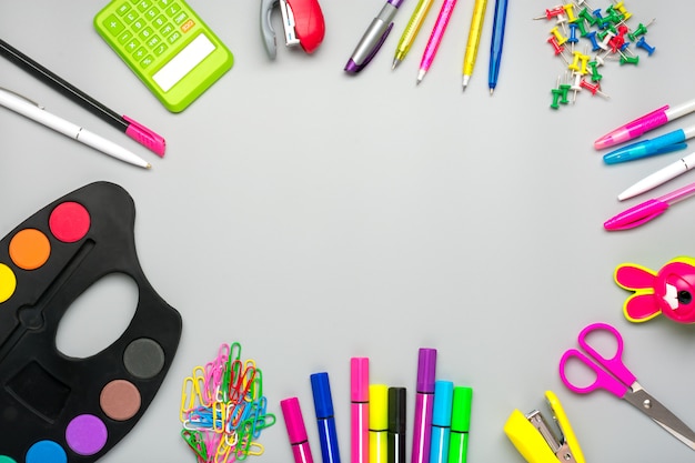 Frame from school and office supplies Paper clips, scissors, pens, felt-tip pens, sharpener, calculator, stapler isolated on gray background Flat lay