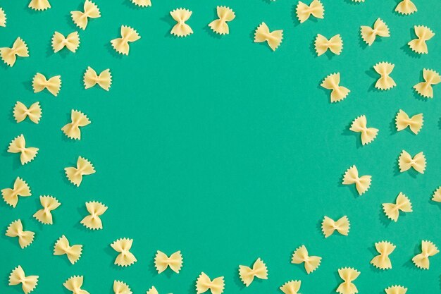 Frame from wheat pasta on green background Random pattern Flat lay