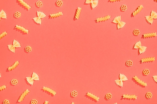 Frame from wheat pasta on red background Random pattern Flat lay