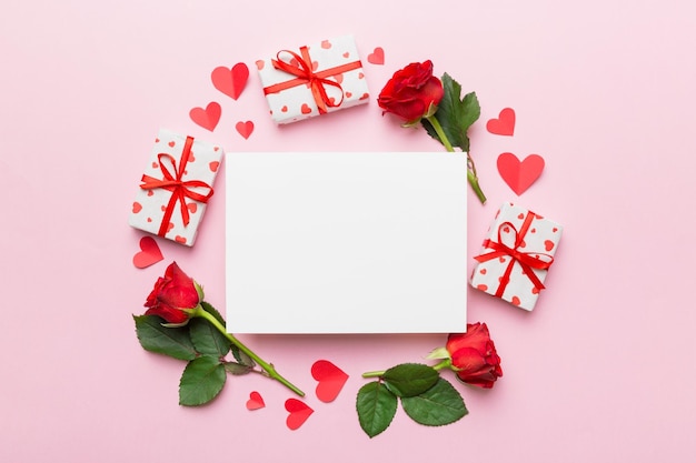 Frame gemaakt van rose git box hart en blanco wenskaart mockup op gekleurde achtergrond Bovenaanzicht plat lag kopie ruimte Holiday Mothers Day verjaardag concept