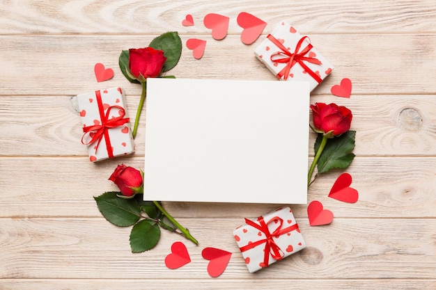 Frame gemaakt van rose git box hart en blanco wenskaart mockup op gekleurde achtergrond Bovenaanzicht plat lag kopie ruimte Holiday Mothers Day verjaardag concept