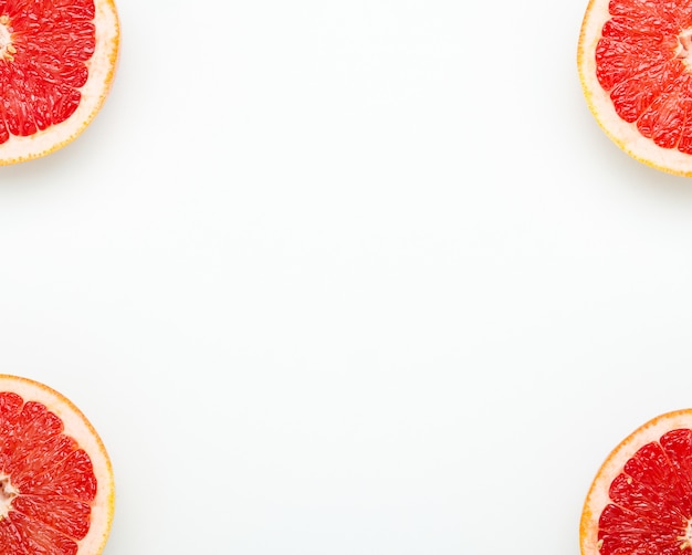 Frame of grapefruit halves on white.