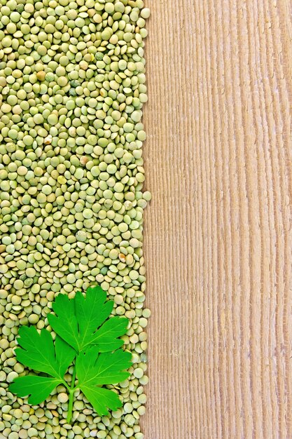 Frame of green lentils with parsley leaf on the left side of wooden boards