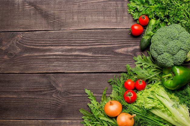 Frame of green and red fresh vegetables on wooden table, top view, copy space