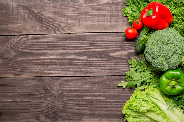 Frame of green and red fresh vegetables on wooden table, top view