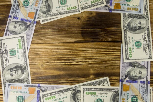 Frame of hundred dollar bills on wooden background