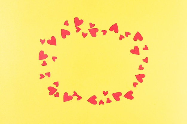 Photo frame for inscriptions from red cut out and paper hearts on a yellow background greeting