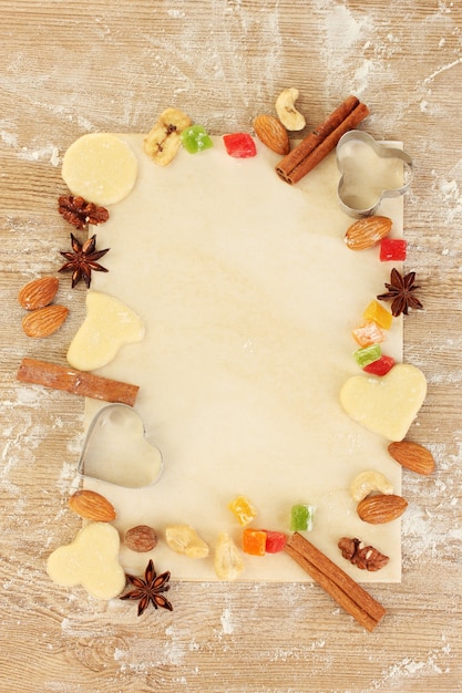 Foto cornice composta da frutta candita, noci, biscotti crudi e stampini per biscotti