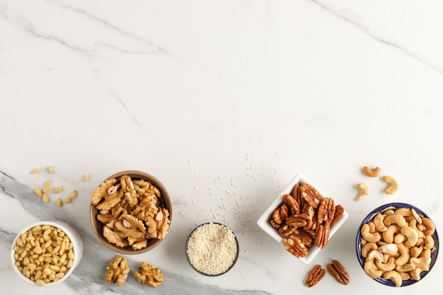 Frame made of different types of nuts in bowls. Top view. Copy space