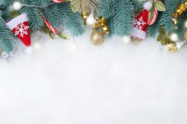 전나무 가지와 크리스마스 장식으로 만든 프레임은 복사 공간이 있는 눈 덮인 배경에 평평하게 놓여 있습니다.