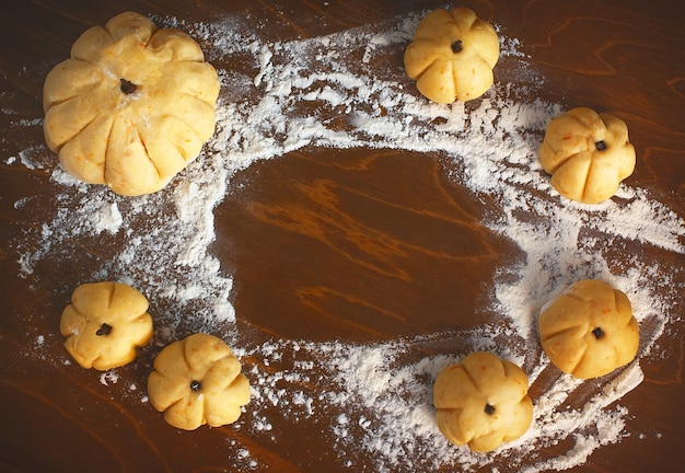 Foto cornice fatta di farina e pasta cruda a forma di zucche su un tavolo di legno