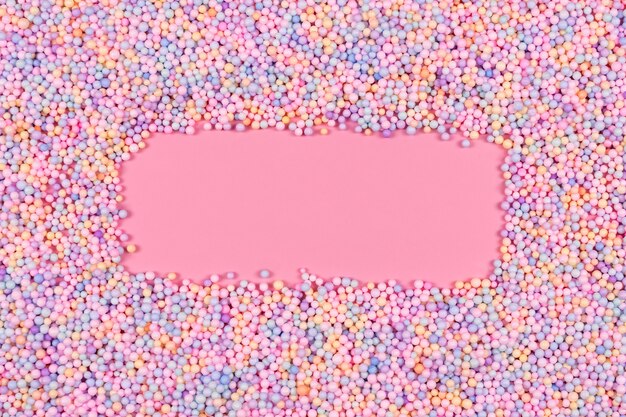 Frame made of pastel color balls on pink styrofoam or polystyrene foam