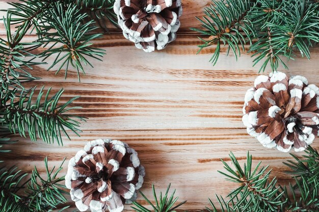 Frame made of pine cones and fir branches on a wooden background. Postcard. Copy space. Flat lay. View from above