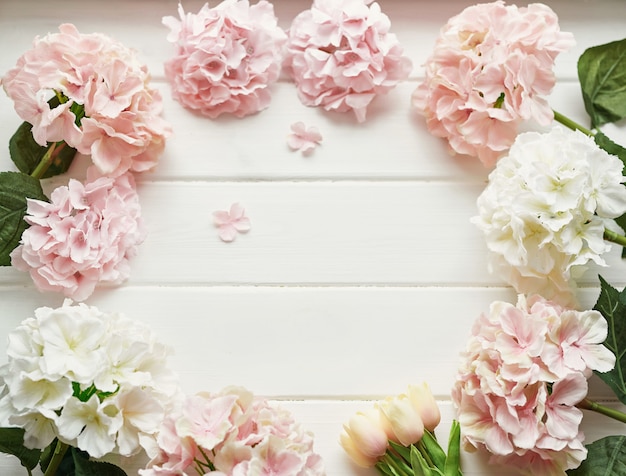 Frame made of pink and beige hydrangea flowers and yellow tulips