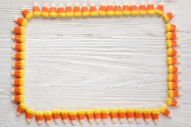 Frame made of tasty Halloween candies on light wooden background