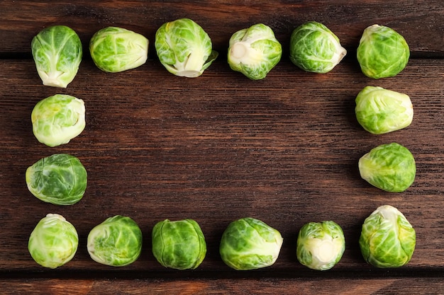 Photo frame made with brussels sprouts on brown wooden table flat lay space for text